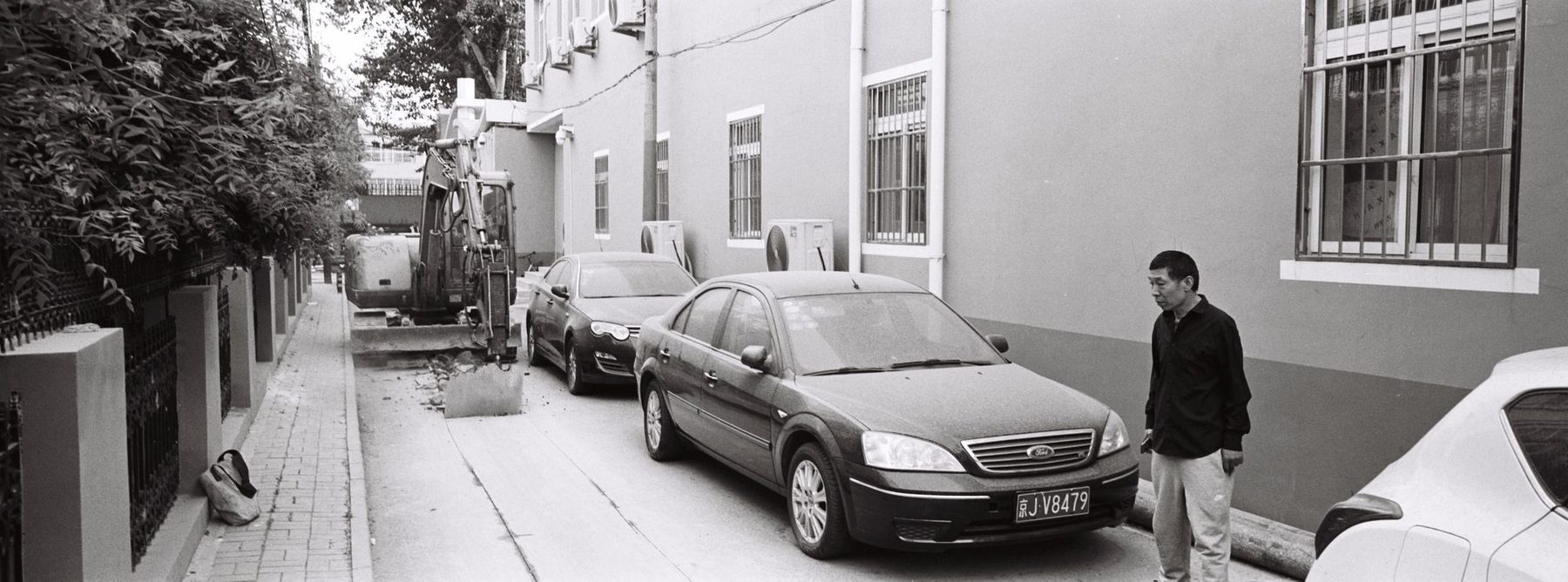 A man walking past parked cars on a residential street